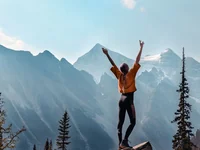 Девушка раскинула руки в горах